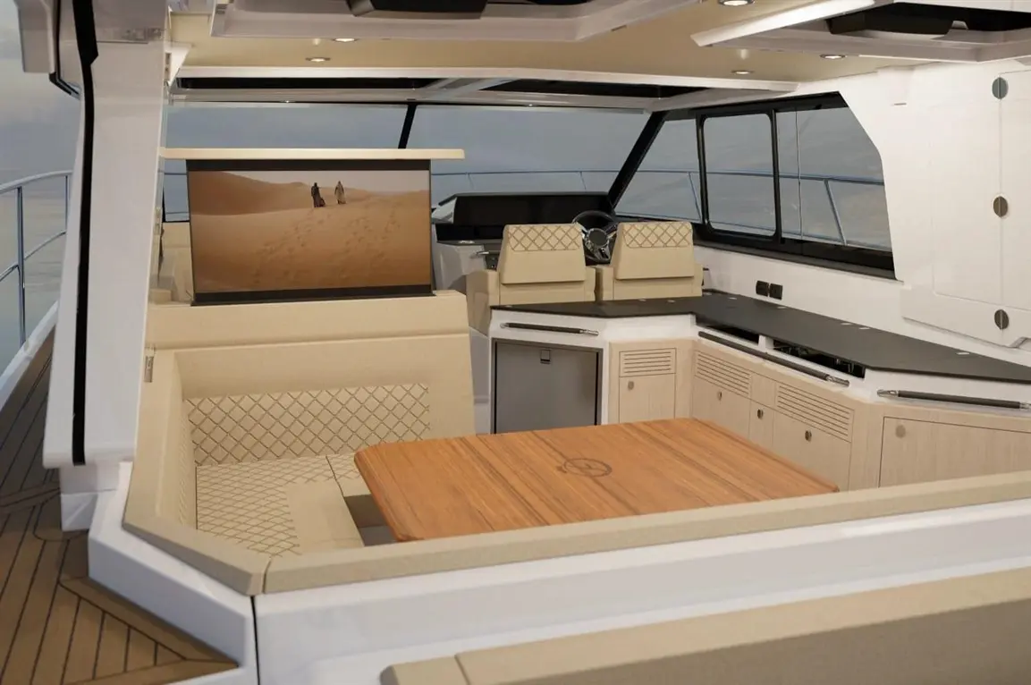 Luxurious yacht interior featuring a dining area, modern kitchen, and a large screen displaying a desert scene.